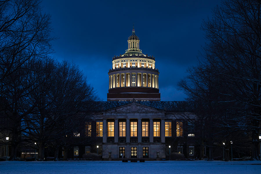 An exterior view of Rush Rhees Library from the Eastman Quad at night.