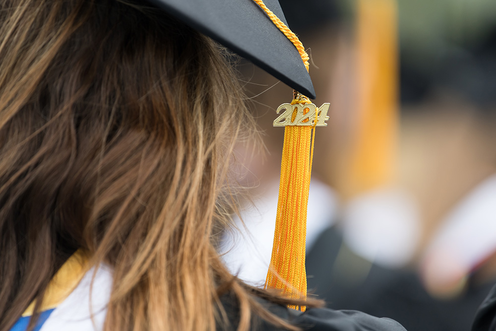 A close up of the back of a person's head who is wear a graduation cap.
