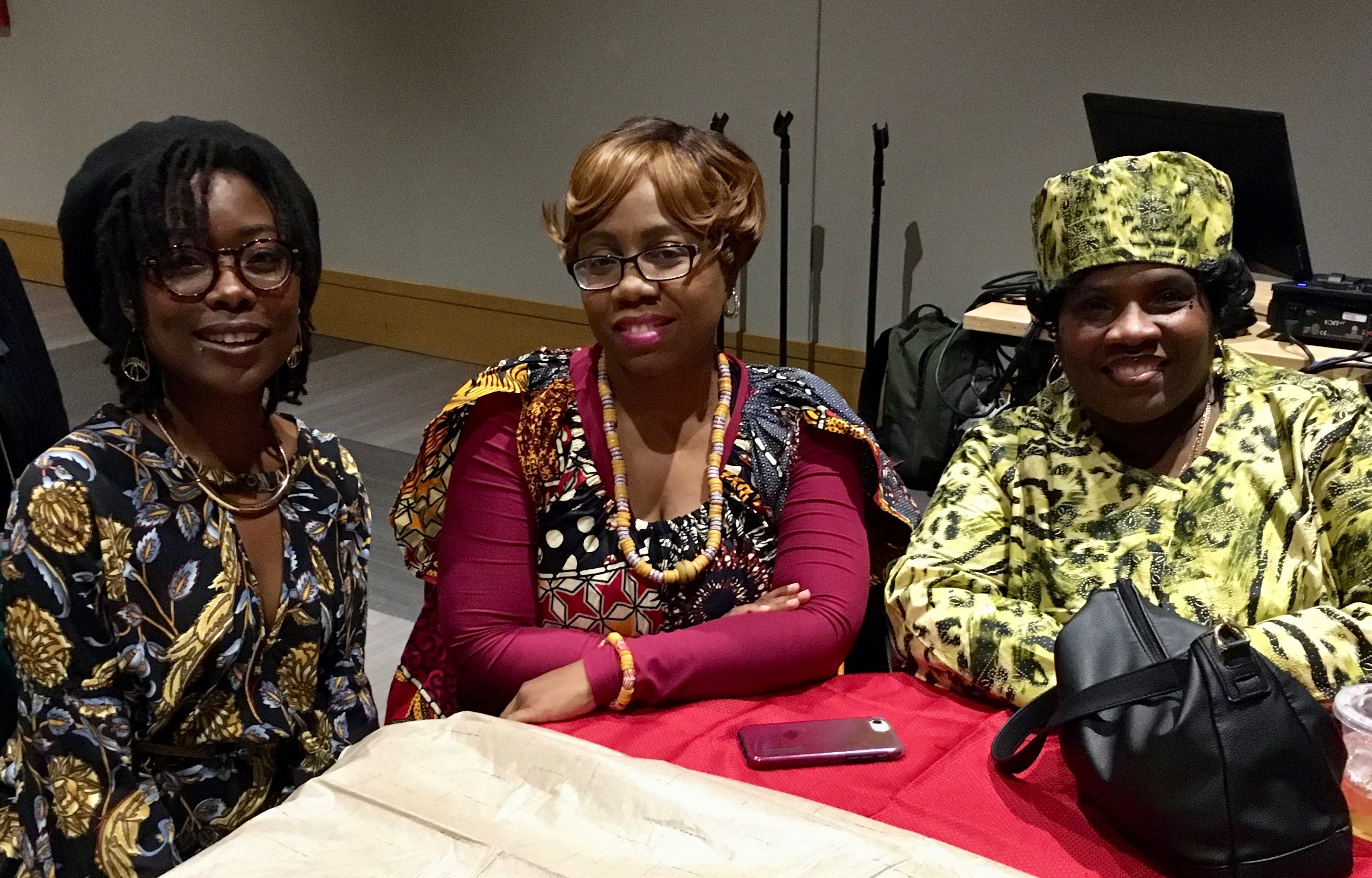 three smiling African American women wearing print fabrics