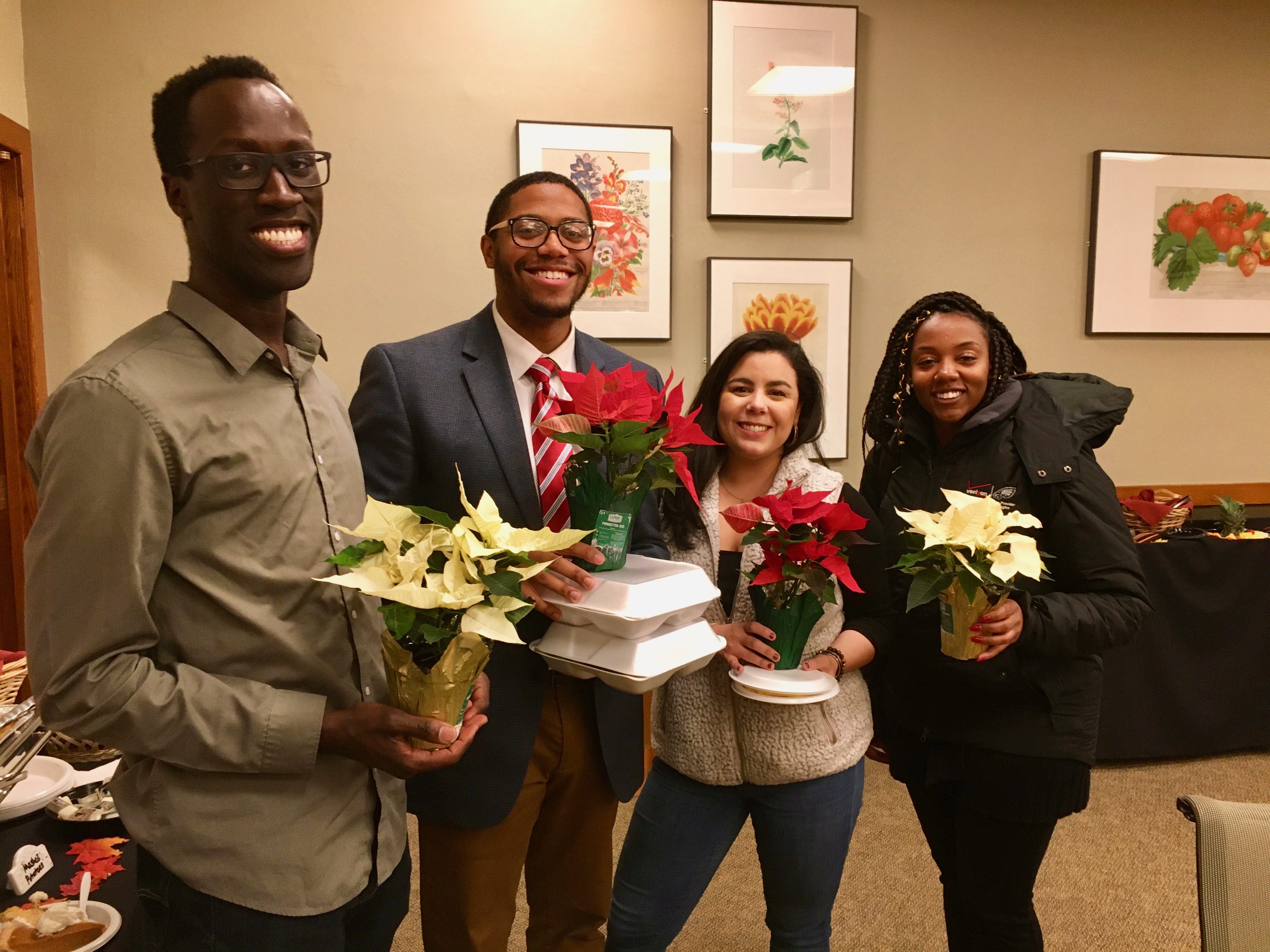 4 graduate students holding poinsettia flowers