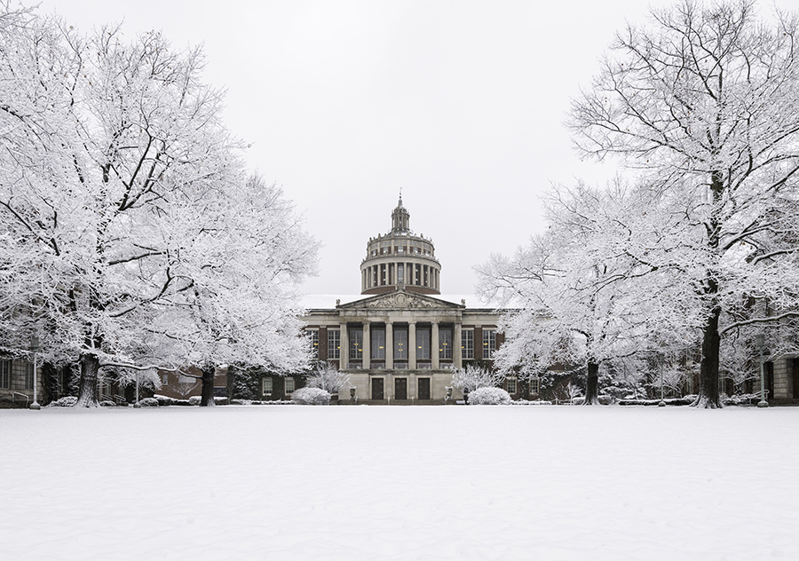 An exterior view of Rush Rhees Library from the Eastman Quad covered in snow.