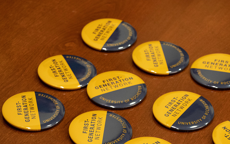 Buttons that read University of Rochester First-Generation Network sit on a table