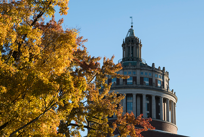 Photo of a woman taking a photo of a man posing with University of Rochester mascot, Rocky