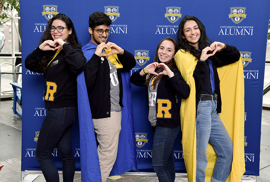 Photo of Student Alumni Ambassadors posing in front of a backdrop making hearts with their hands