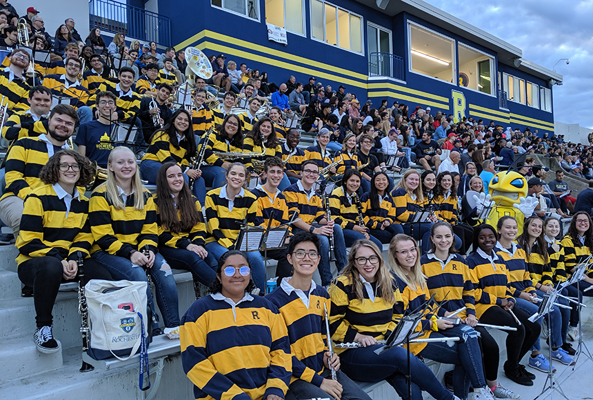 Photo of Pep Band posing seated on bleachers in Fauver Stadium