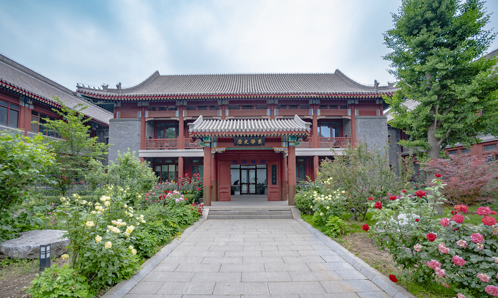 An exterior view of a building in traditional Chinese-style architecture with a walkway and gardens.