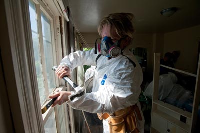 woman stripping lead paint from a window