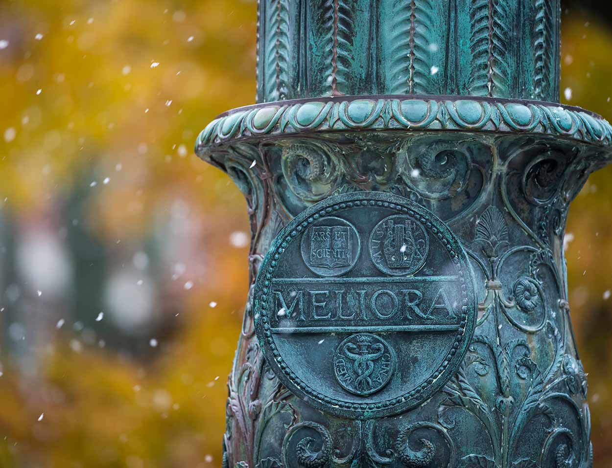 Meliora seal on flagpole in snow at University of Rochester