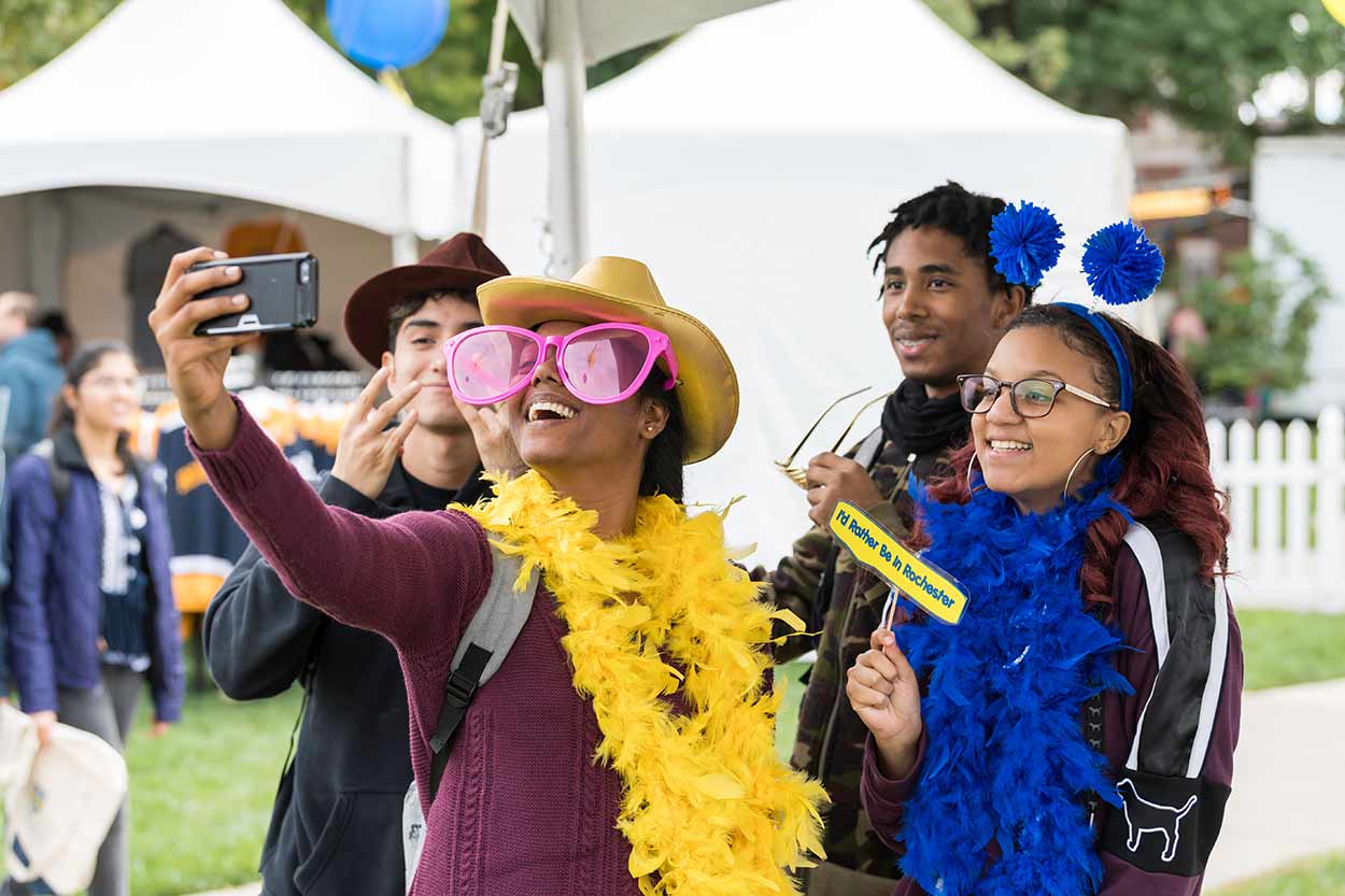 Students wearing costume props taking a selfie at University of Rochester Meliora Weekend