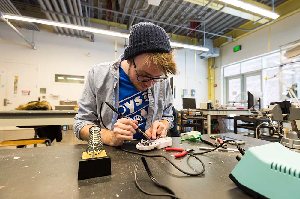 Student soldering electronics as part of tuition free program at University of Rochester