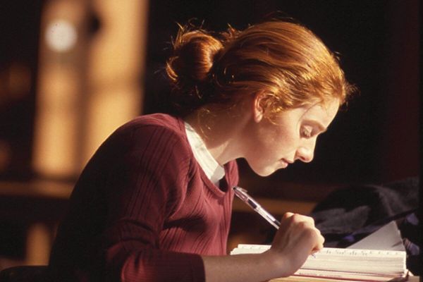 A student at a desk writing in a notebook