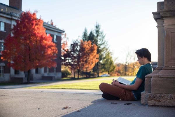 Student sitting on campus of Unversity of Rochester