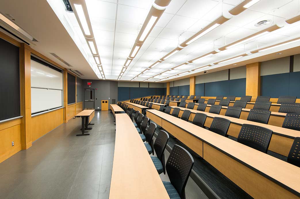 large, empty classroom shows seats, desks, screen.