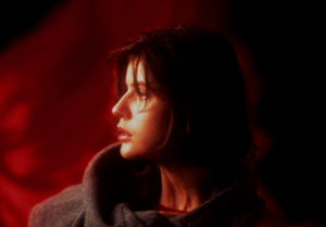 Screenshot of Three Colors: Red. A woman against a red background, looking to the left.