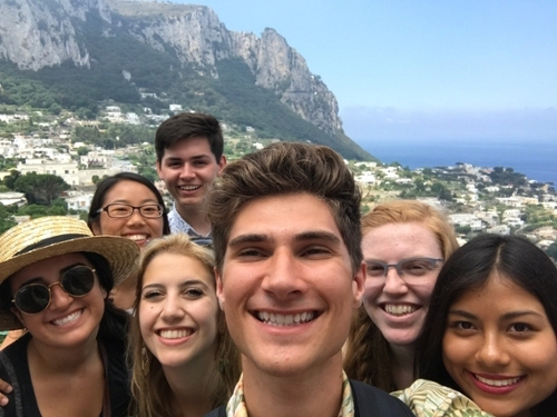 A group of seven students pose for the camera with a mountain in the background.