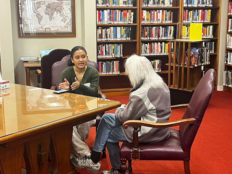 Two people having a conversation at a desk.