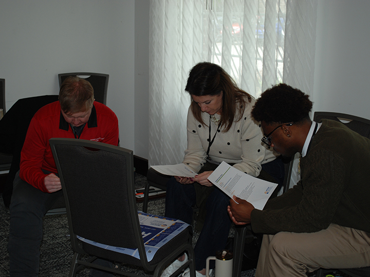 Three people bent over papers.