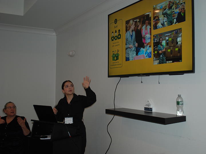 A presenter gesturing towards a screen.