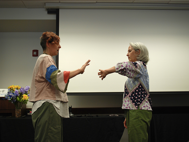 Two people facing each other while holding out their hands.