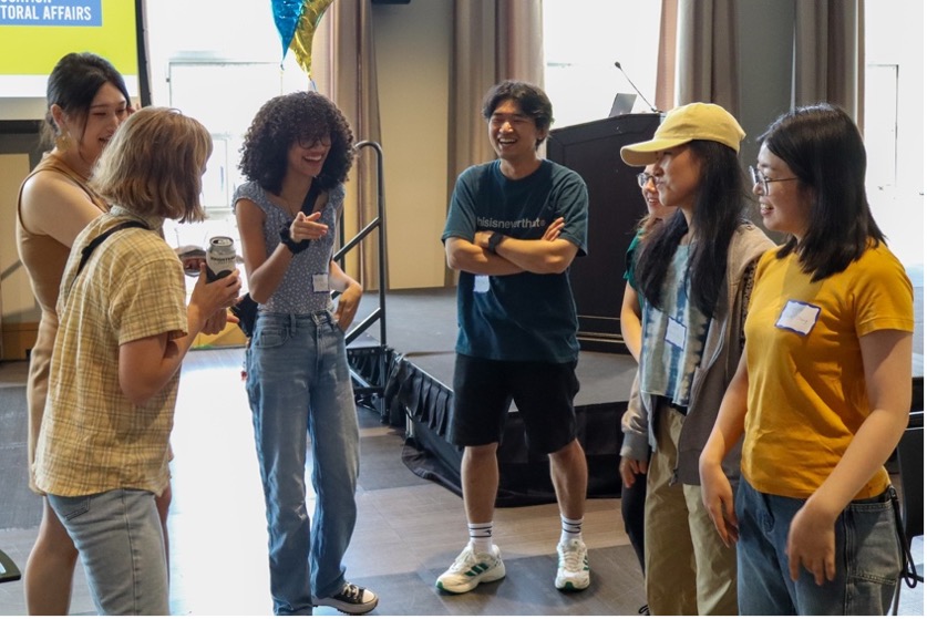 A group of people talking and laughing in front of a stage.