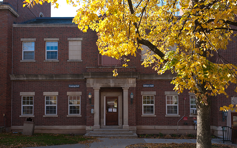 Door to residence hall with a tree with yellow leaves in the foreground