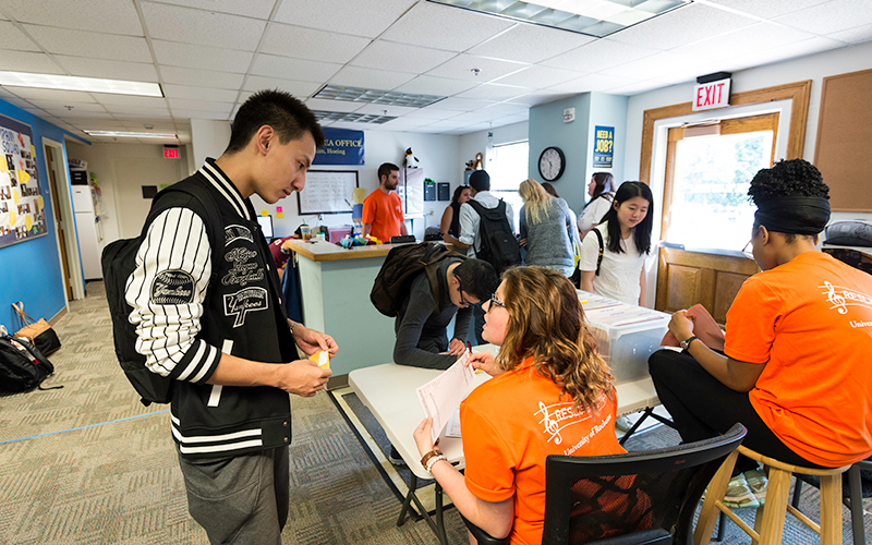 Photo of a student talking with a Residential Life student staff member in a residential area office