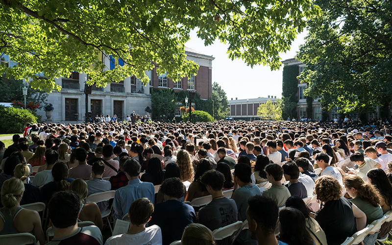 Photo of the stage on Eastman Quad at a past Convocation with leaves in the foreground