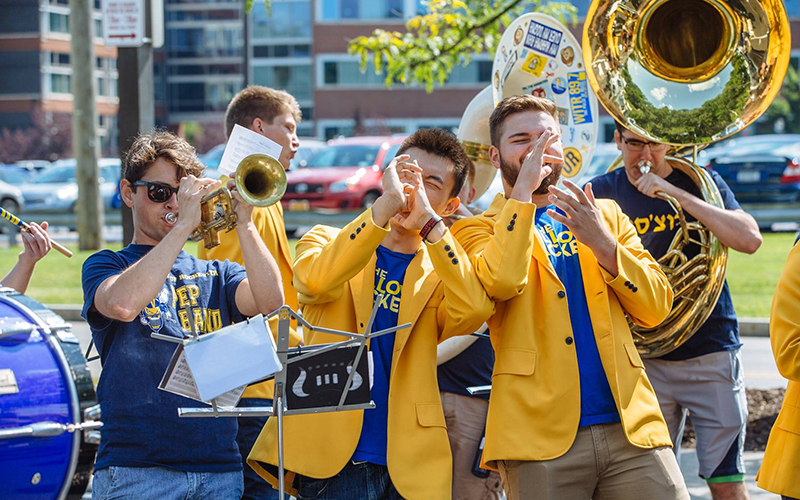 Photo of members of the YellowJackets a cappella group and the Pep Band performing at move-in during a past Fall Welcome Week