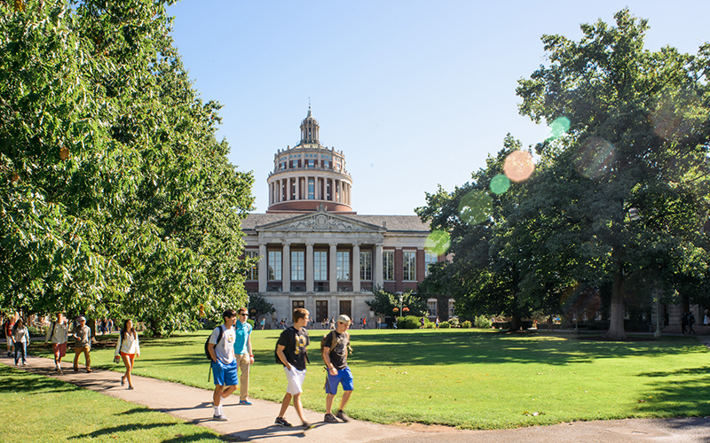 Photos of students walking across the Eastman Quad between classes on a sunny day