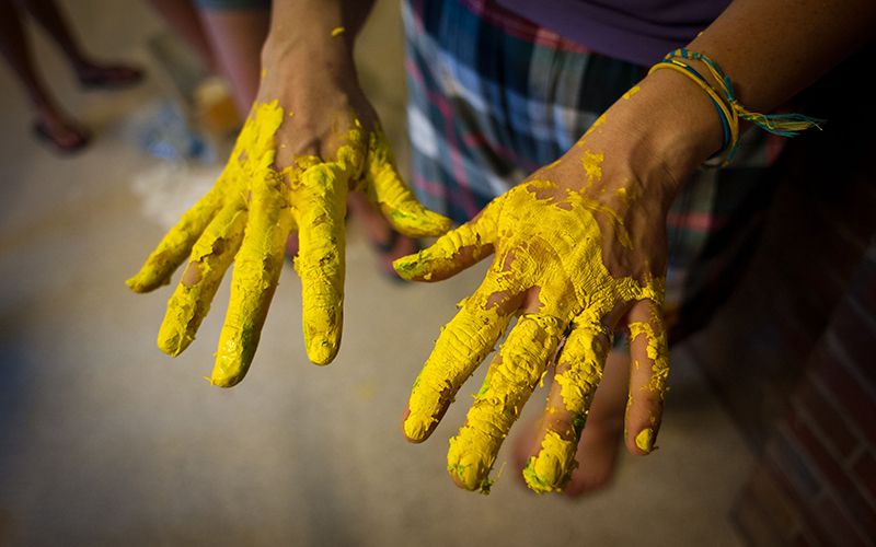 Photo of two hands covered in yellow paint