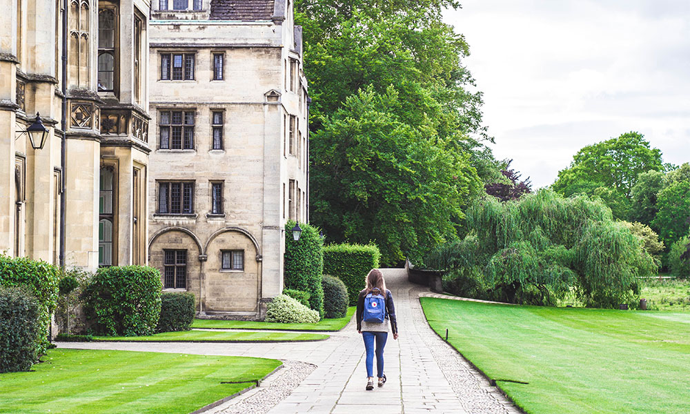 A student walking a path at King's College, University of Cambridge, UK.