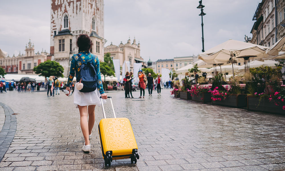 A student walking across a plaza with a suitcase. (Getty Images)