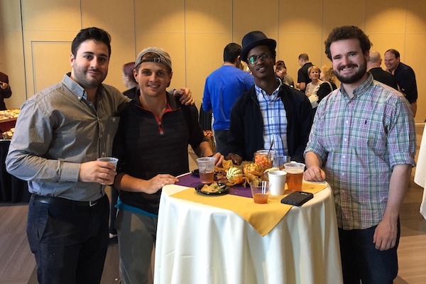 Four men smiling together while eating and drinking