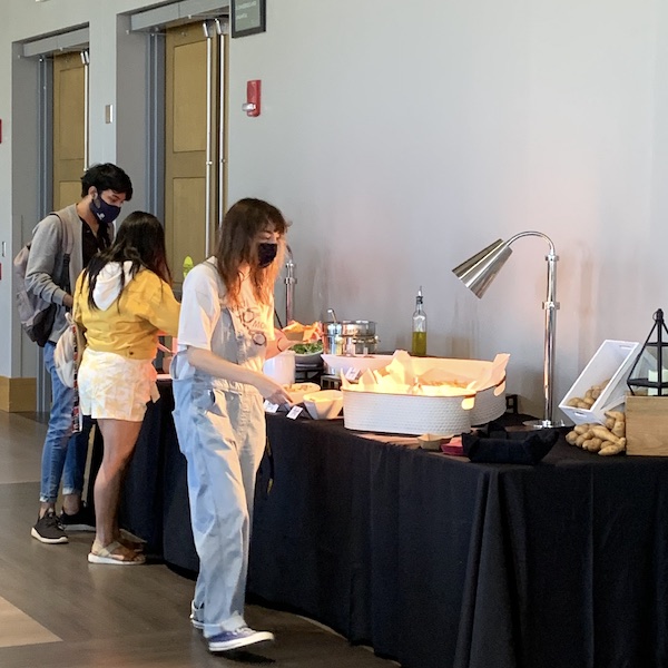 A buffet with three people selecting food