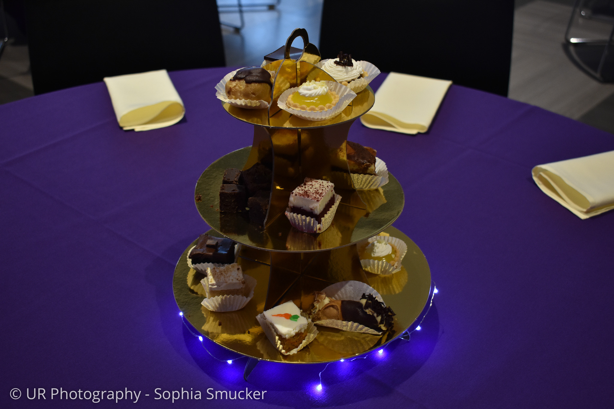 Golden three-tiered tray holding assorted desserts