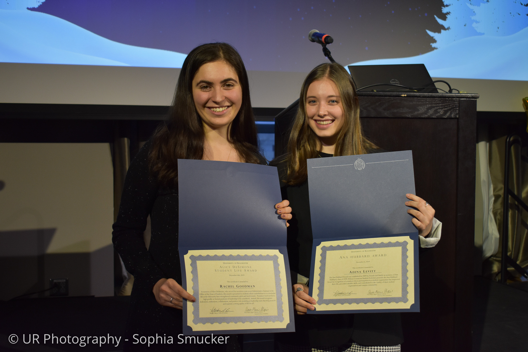 Two students standing with presented certificates while smiling