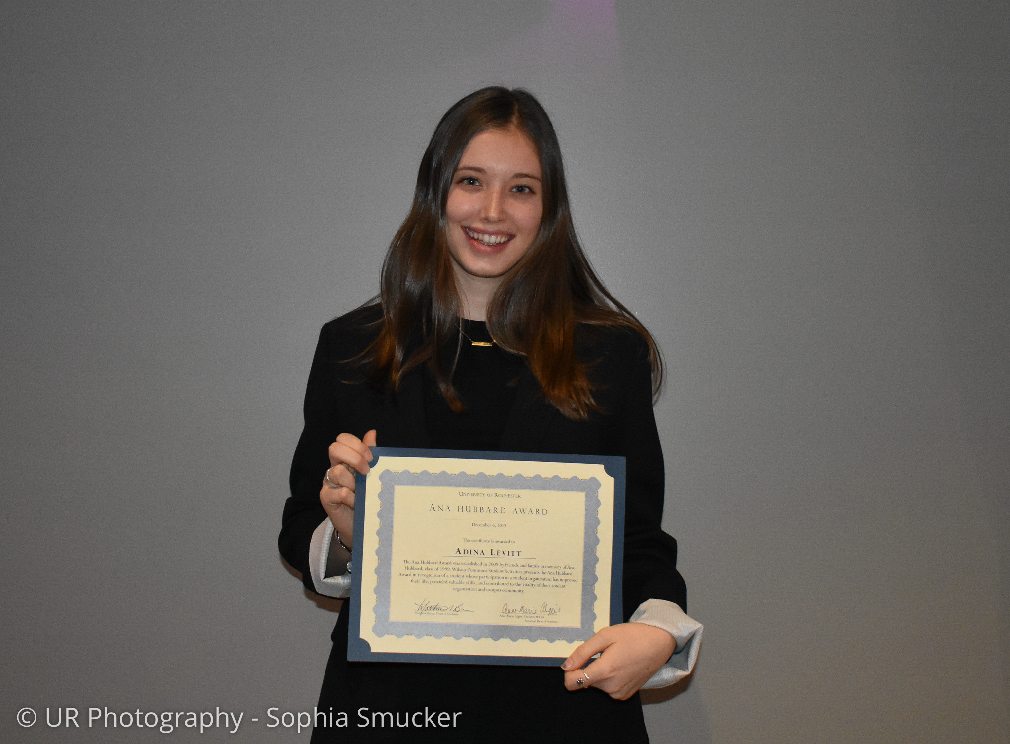 Student holding a certificate while smiling