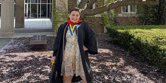 Adira Blumenthal poses outside while wearing her graduation gown.