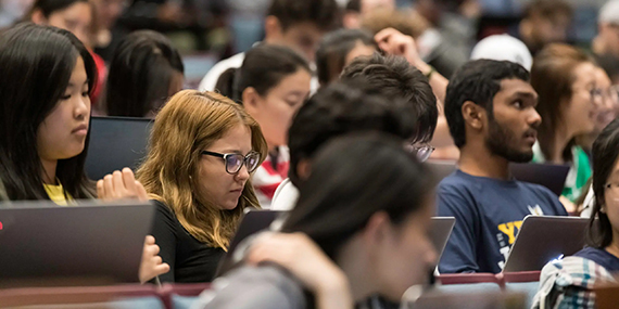 Students sit in a large lecture hall.