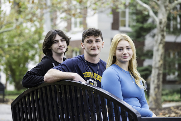 Hudson ’27, Braden ’24 and Nina ’25 Greif are pictured with the memorial bench for their father, Scott, outside Goergen Athletic Center 