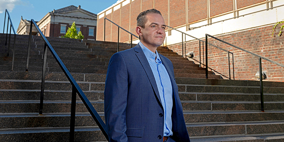 Christopher Kanan stands next to an outdoor staircase on the University of Rochester campus.