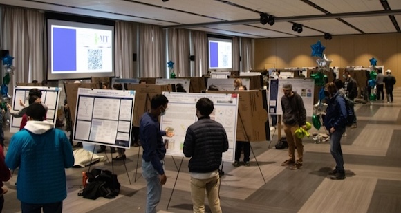 researchers stand at a poster session.