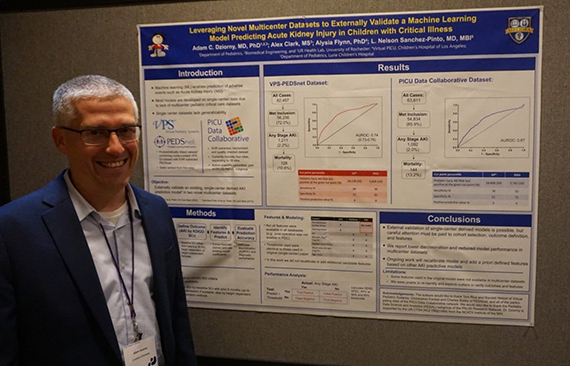Adam Dzorny stands beside a poster about his research.