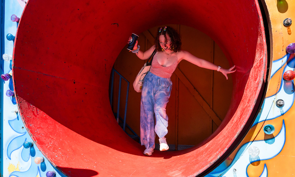 a student negotiates a rotating cylinder while emerging from a fun house