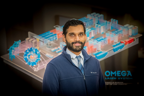 Varchas Gopalaswamy in front of a rendering of the OMEGA Laser System.