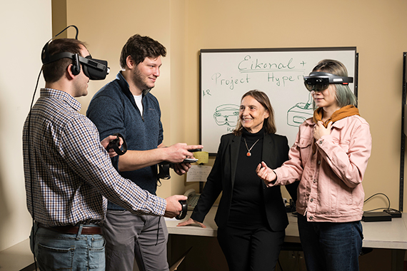 Professor Jannick Rolland stands next to students using VR headsets.