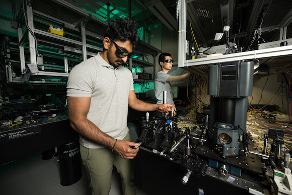 Two optics graduate students in safety glasses in an optics lab