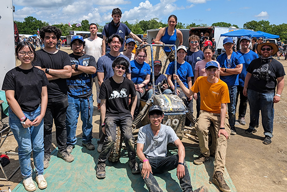 The Yellowjacket Racing team poses with their mud-covered Baja SAE car.