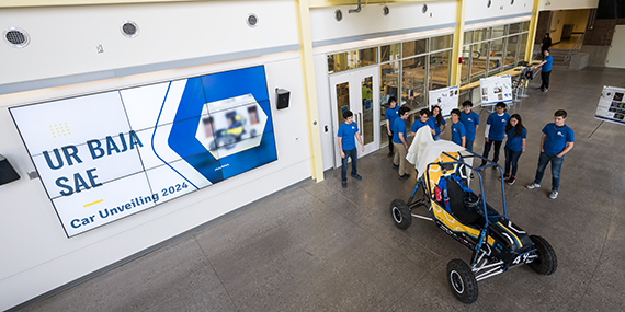 The UR Baja SAE Team removes a sheet to unveil their latest baja car in Rettner Hall.