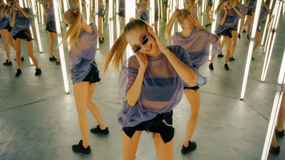 A woman dancing in a hall of mirrors with many reflections behind her.